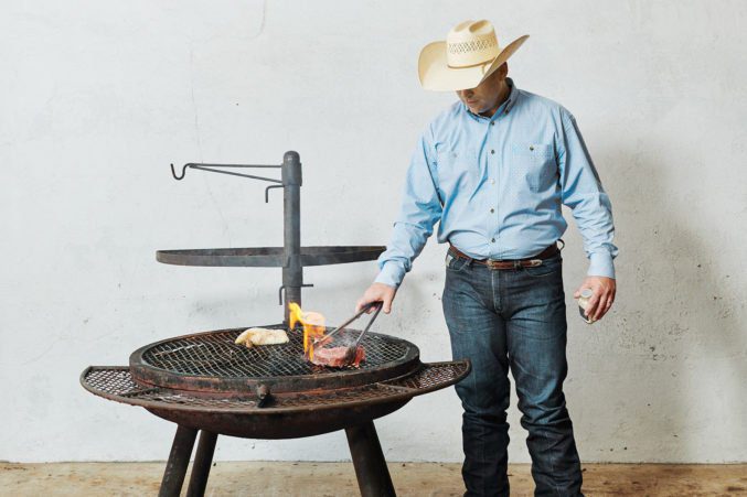 Person in cowboy hat grilling